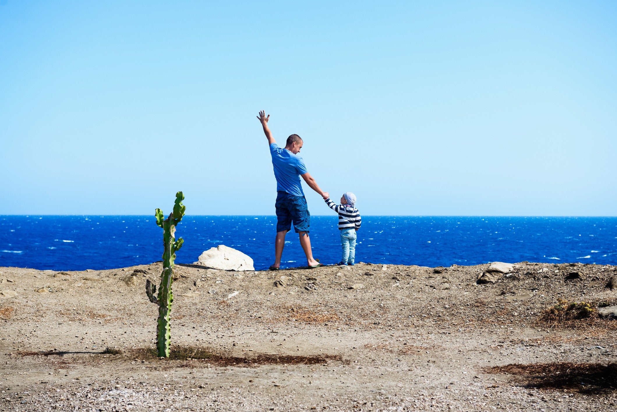 young man and a boy facing the ocean
