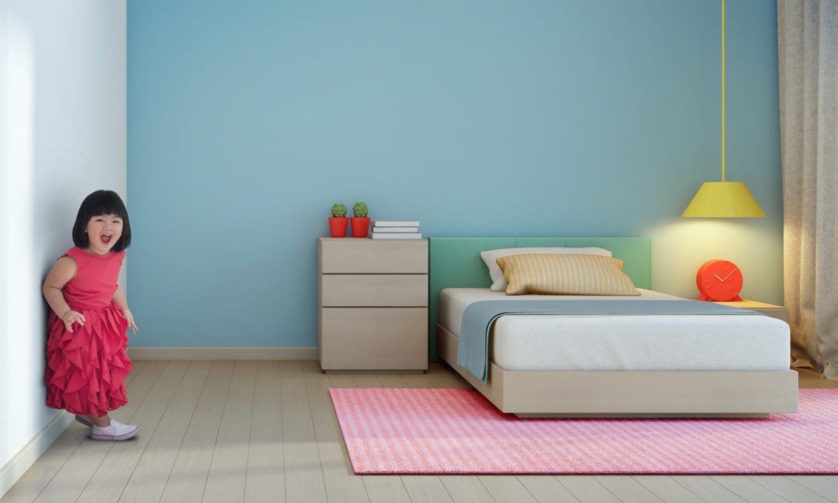 little girl is standing against wall inthe bedroom