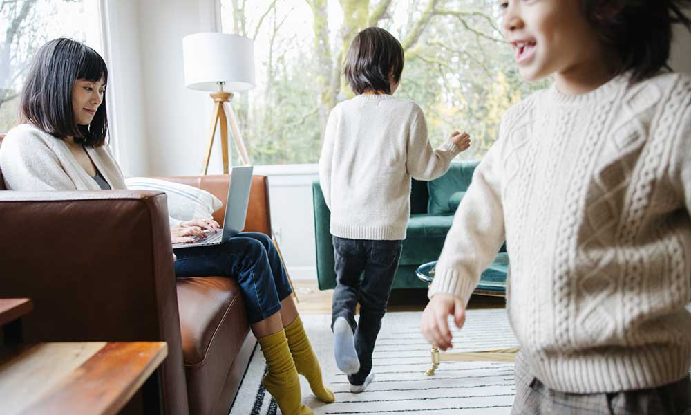 mother working on laptop while kids playing