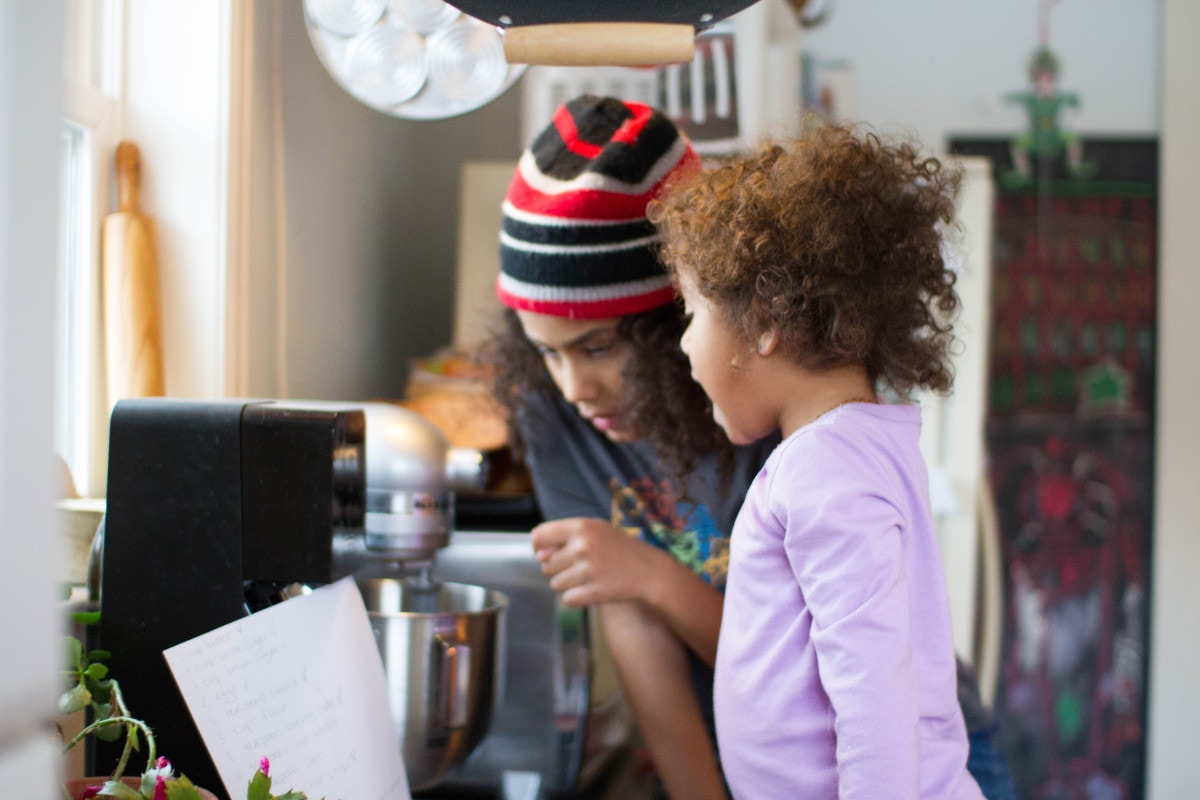 women showing child how to bake