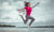 happy young woman jumping in air in front of the sea