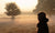 Young Woman Walking On A Road Through A Forest Filled With Fog And Sunlight