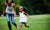 a girl in white dress playing with a young lady in a field