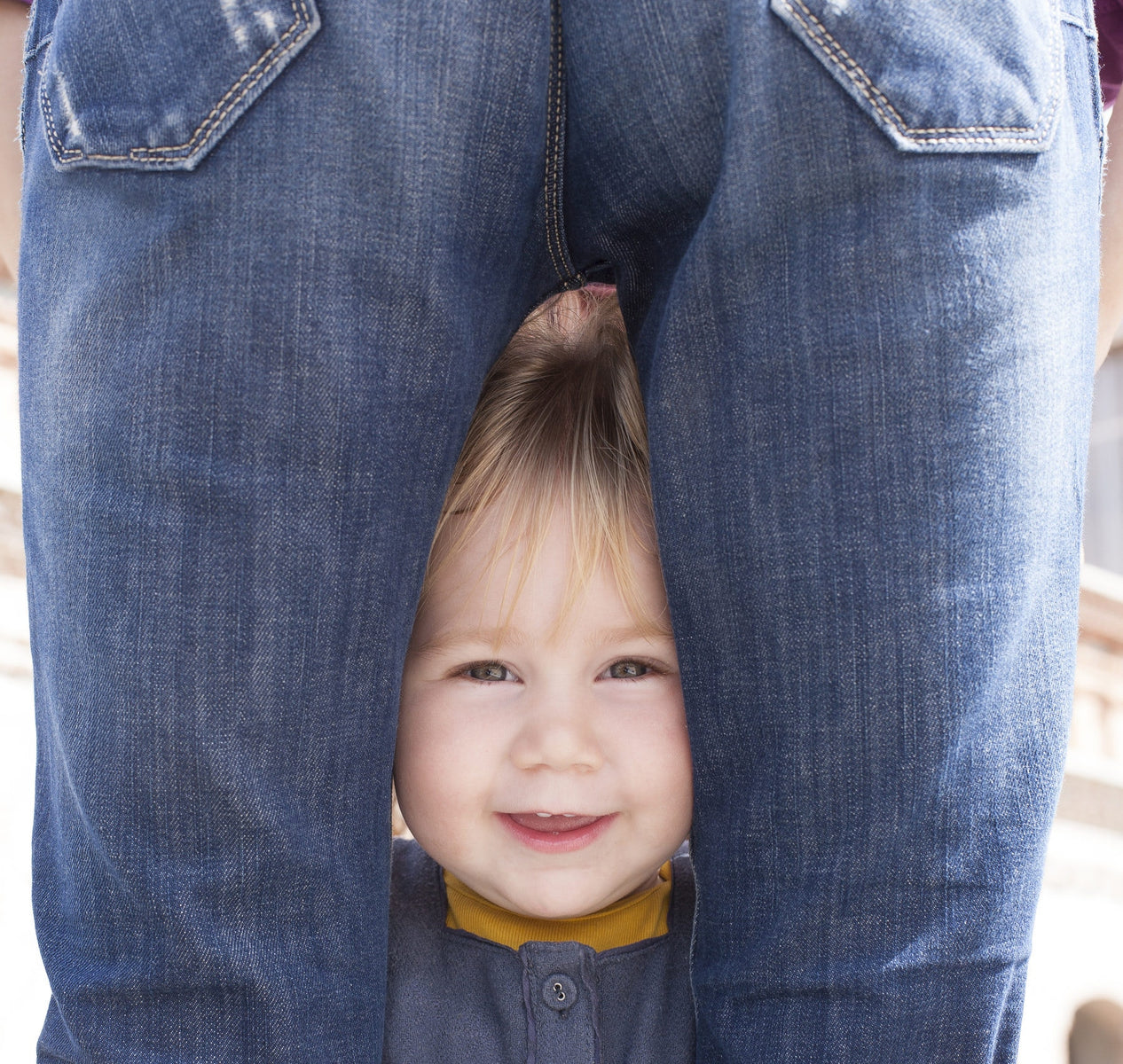 baby standing between parent's leg