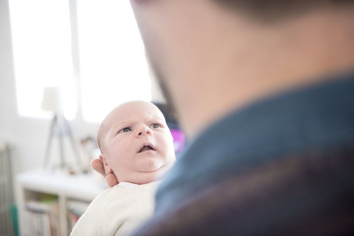 Newborn baby staring at father with surprised expression