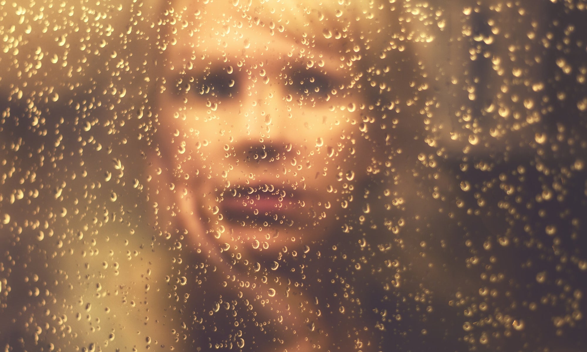 Woman Looking Through Window Covered With Raindrops