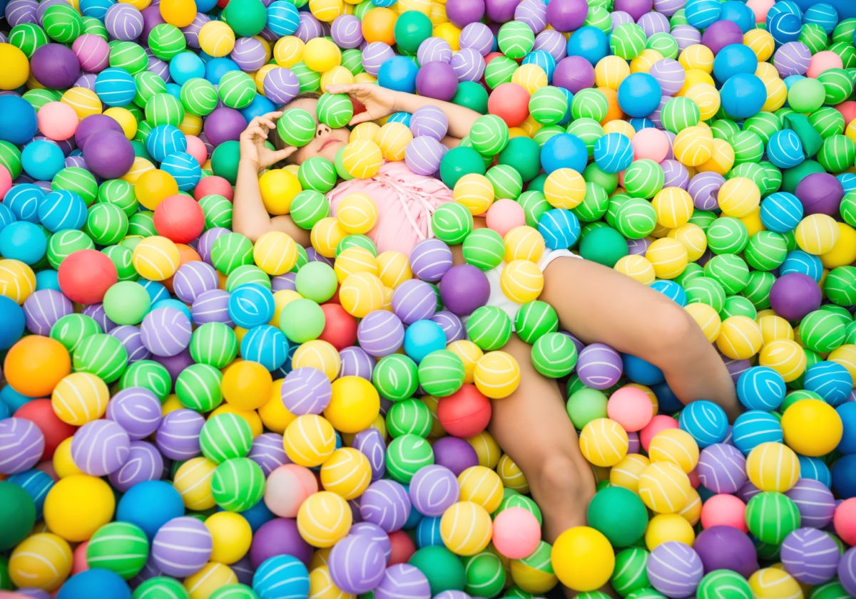 little girl playing lying in colorful balls park playground