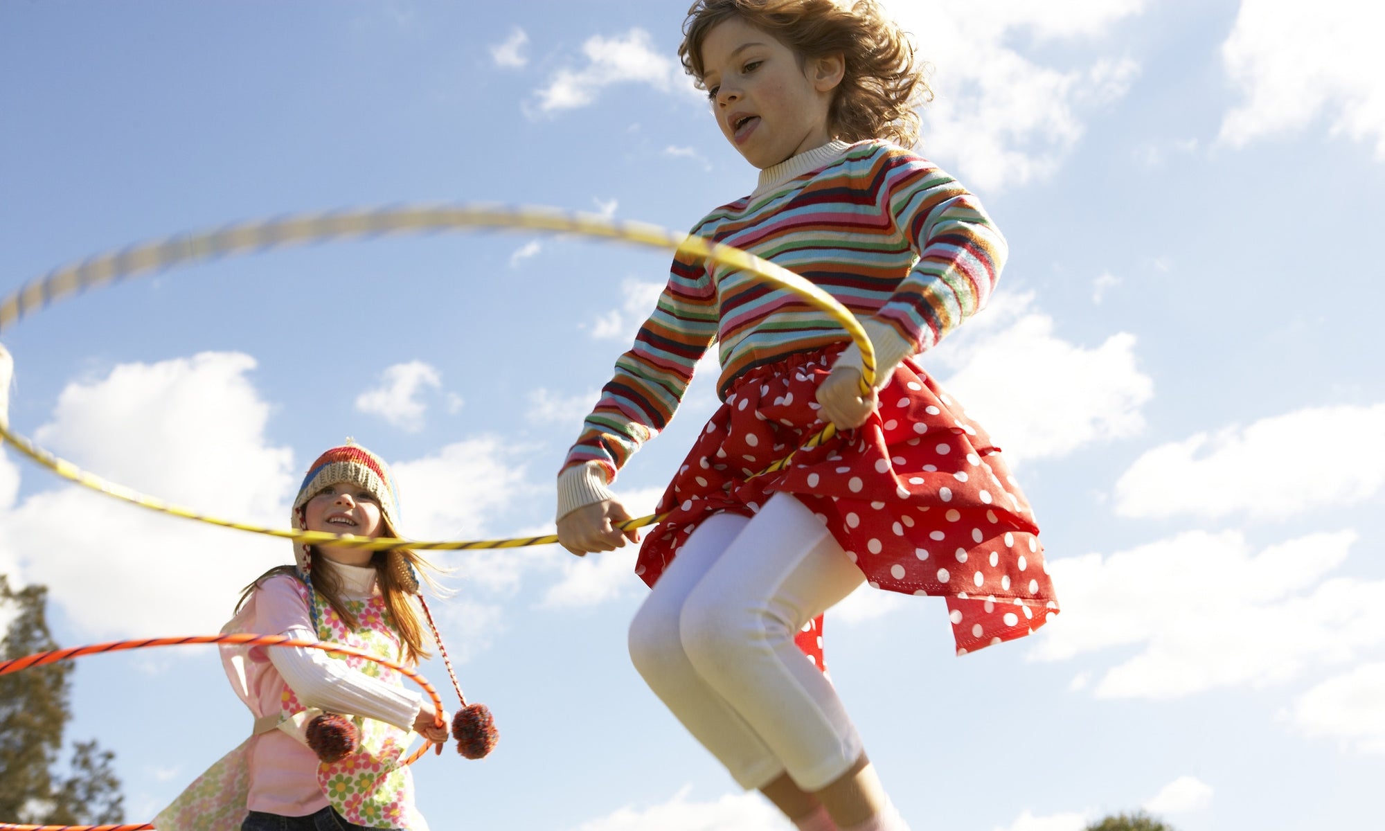 Young Girls playing with hula hoop in summer field