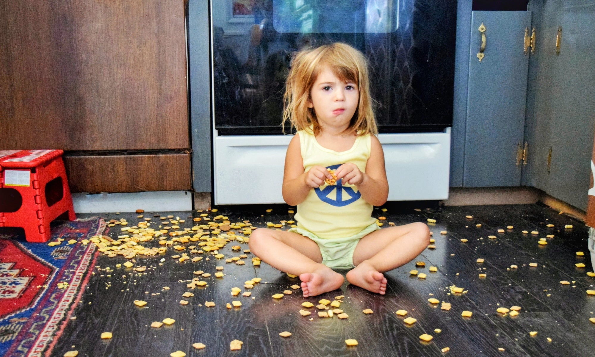 little girl eating snacks off the floor