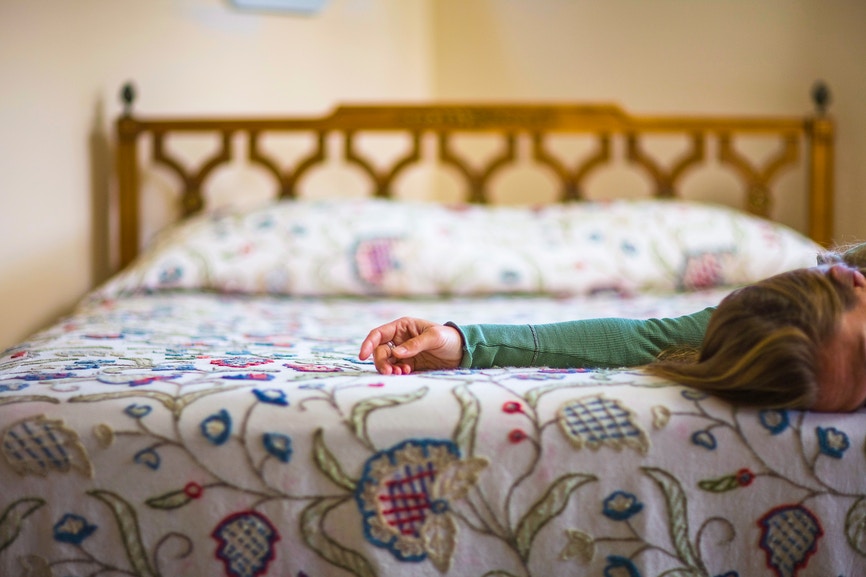 women partially lying on white embroided bed 