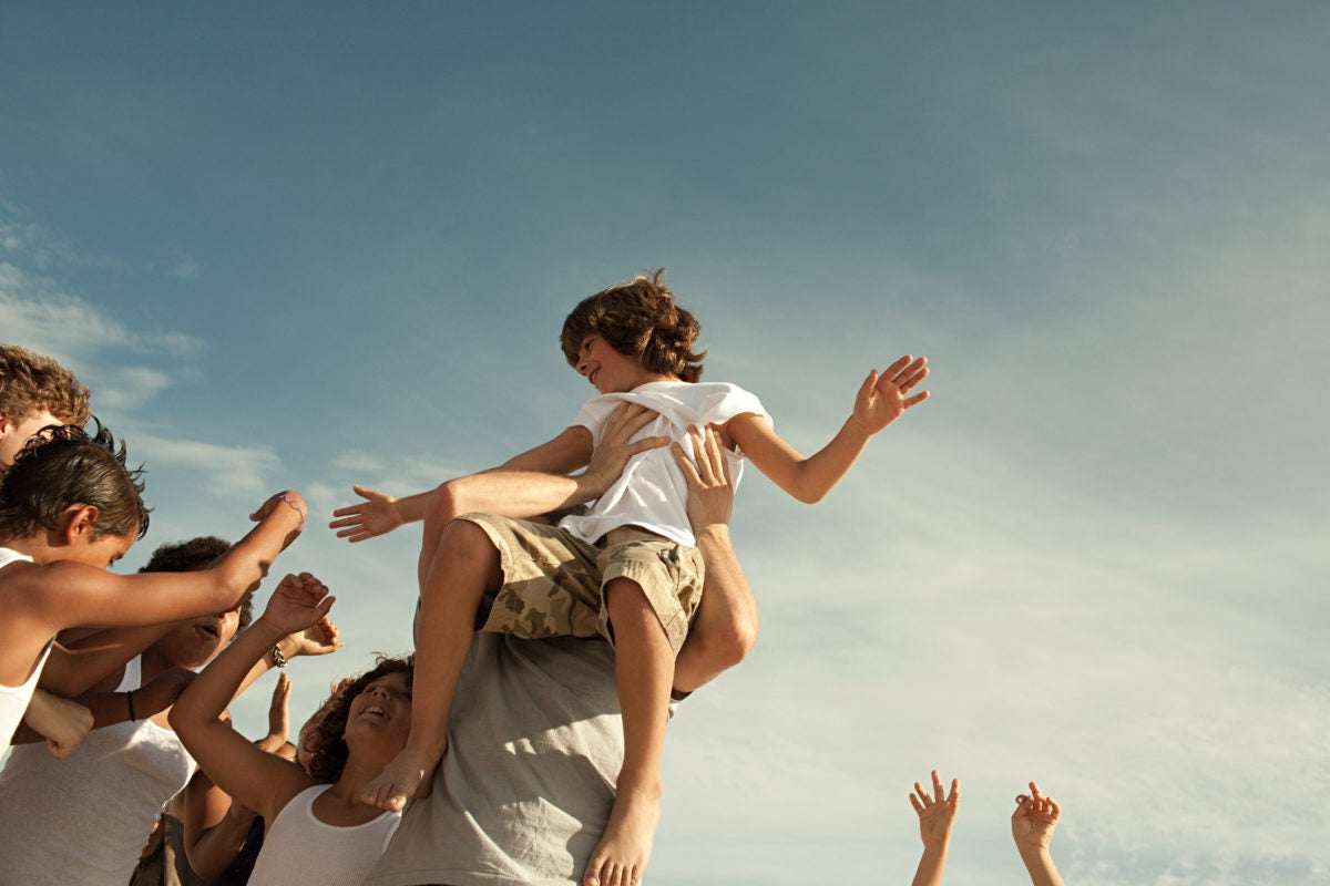 man holding a young boy high in the air