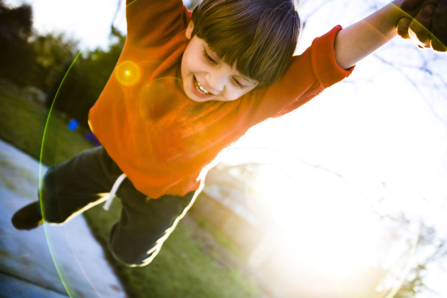 young cheerful boy in orange sweatshirt palying in playground