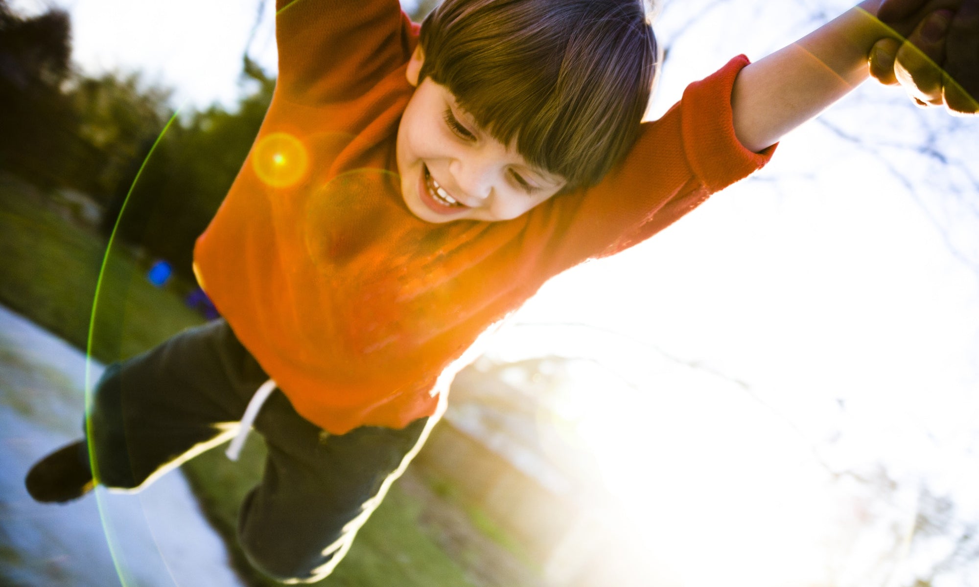 young cheerful boy in orange sweatshirt palying in playground