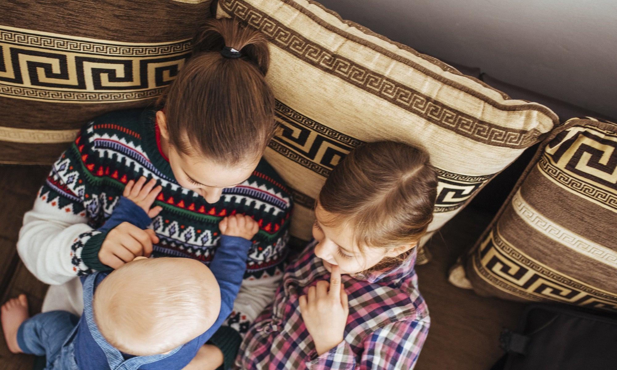 cute sisters with toodler siting on elder sister's lap