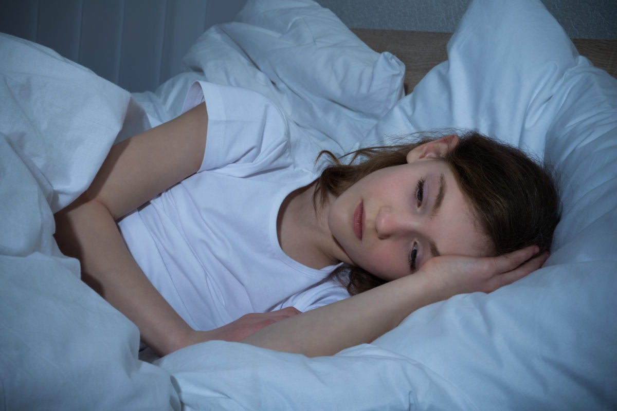 young girl lying alone in bed thinking