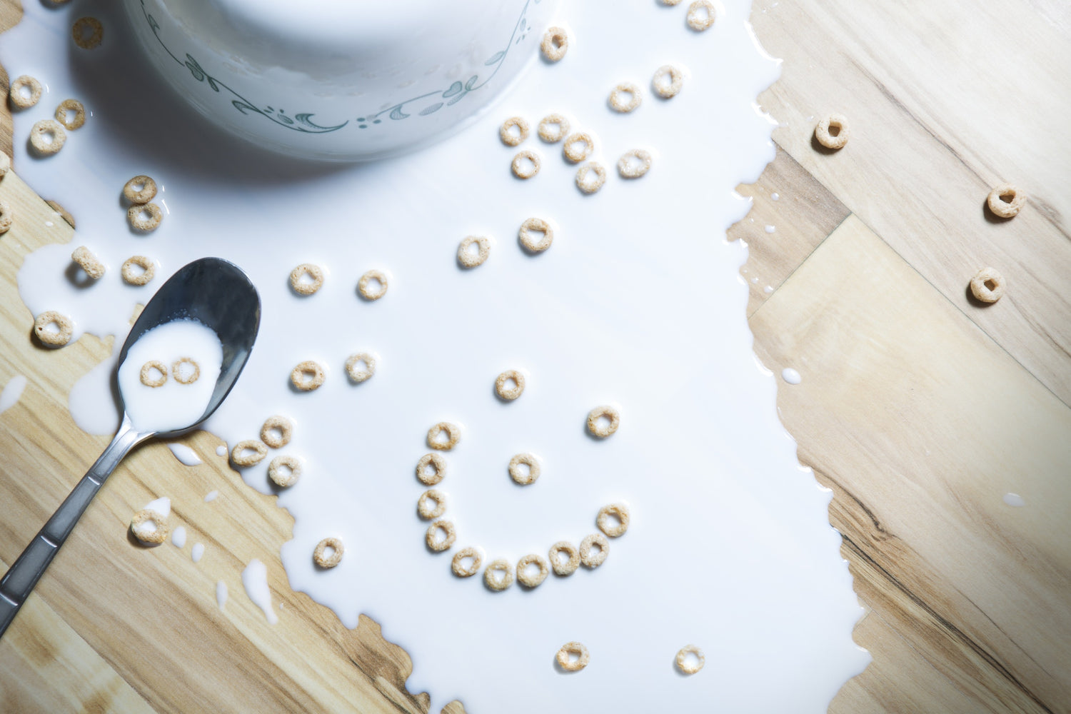 bowl of milk and cereals dropped on a wood table