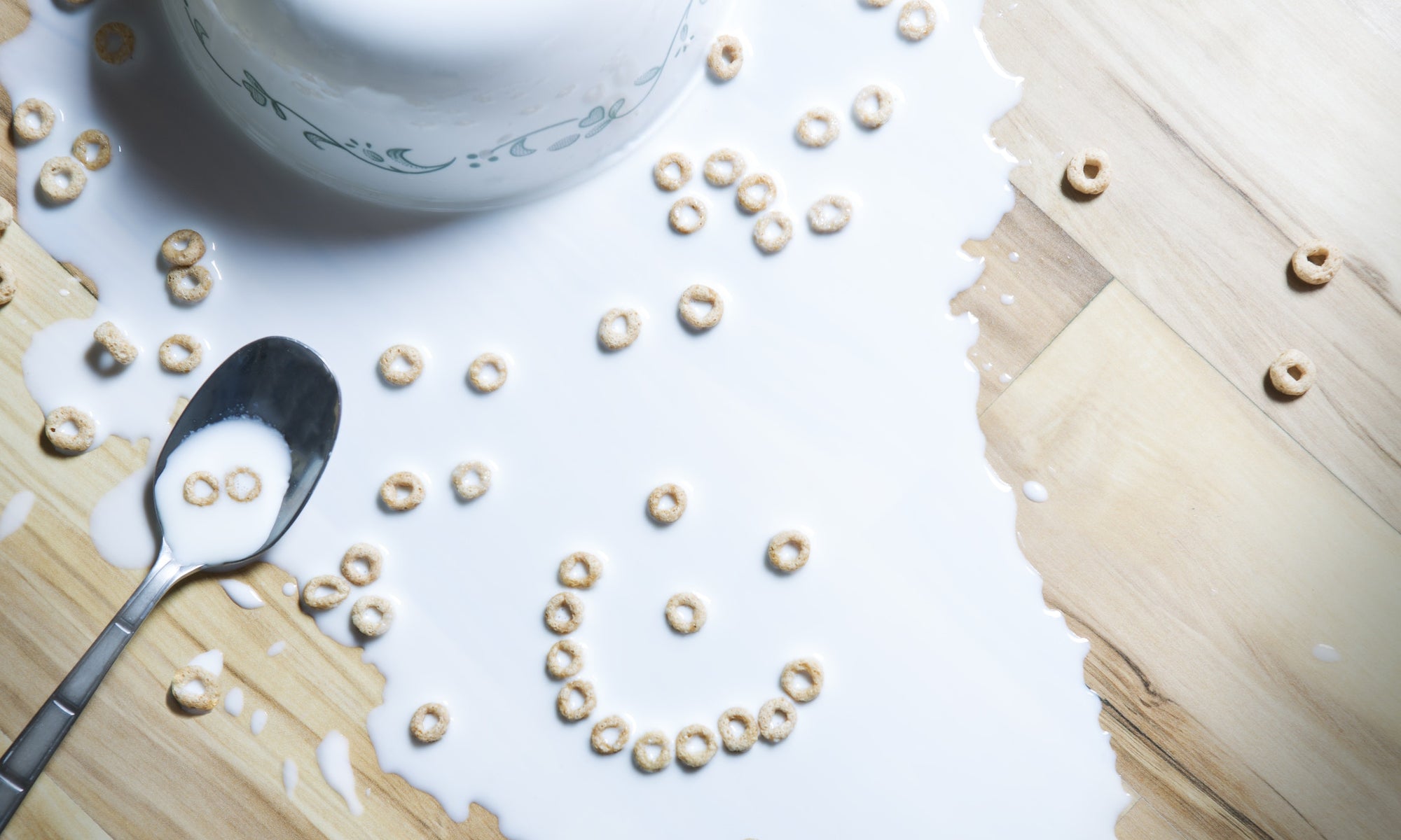 bowl of milk and cereals dropped on a wood table