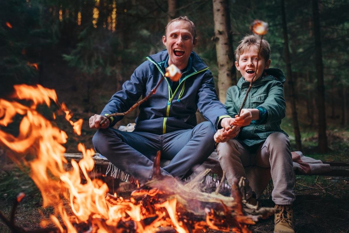 father and son cooking marshmallows at campfire