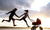 parents jumping in air with child in stroller