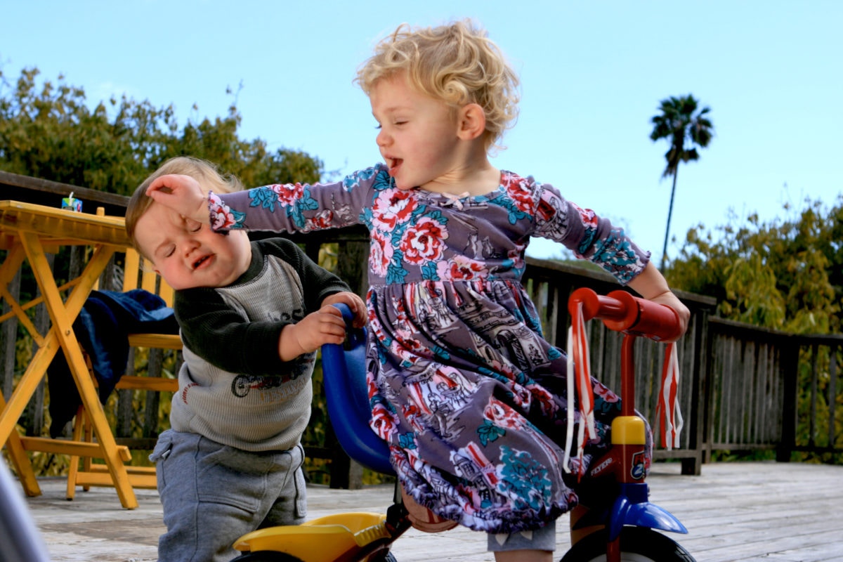 Two kids are playing while one is hitting to another's head