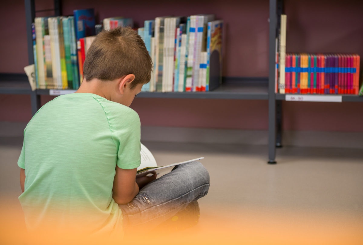 A boy is reading book by sitting alone