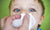 boy with blue eyes blowing nose to tissue