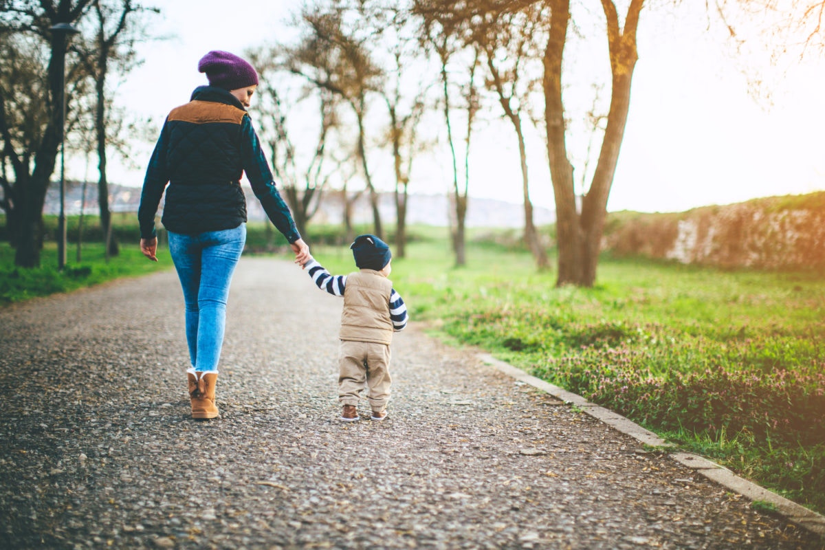 A mother and kid is walking on park by holding hand