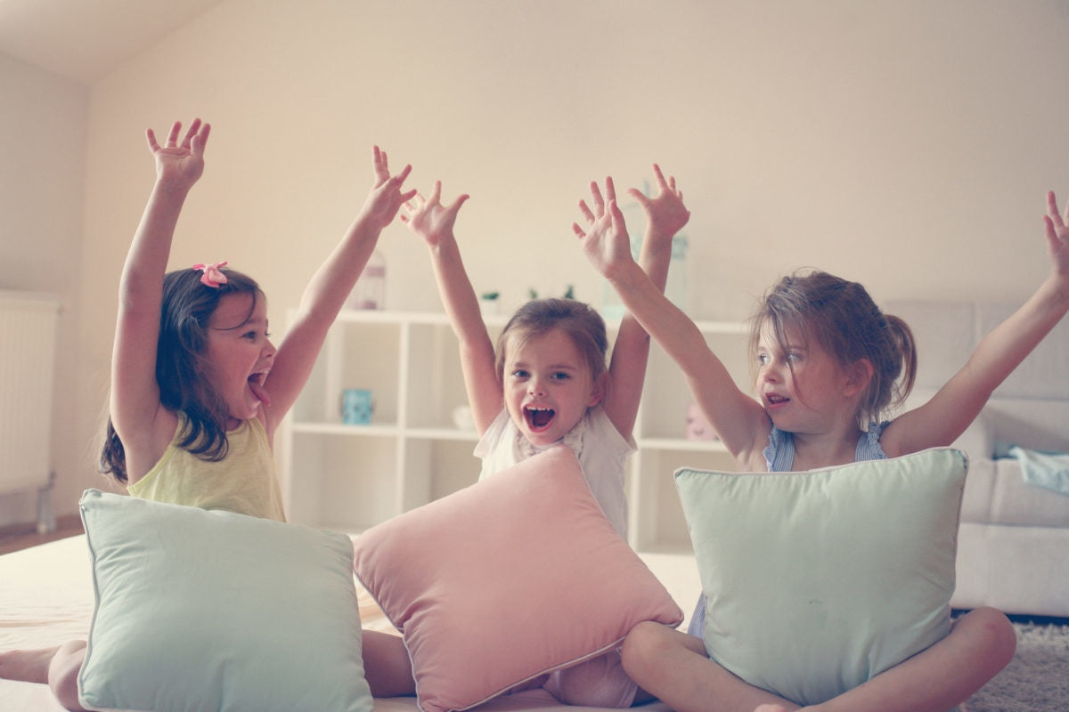 three girls playing on bed