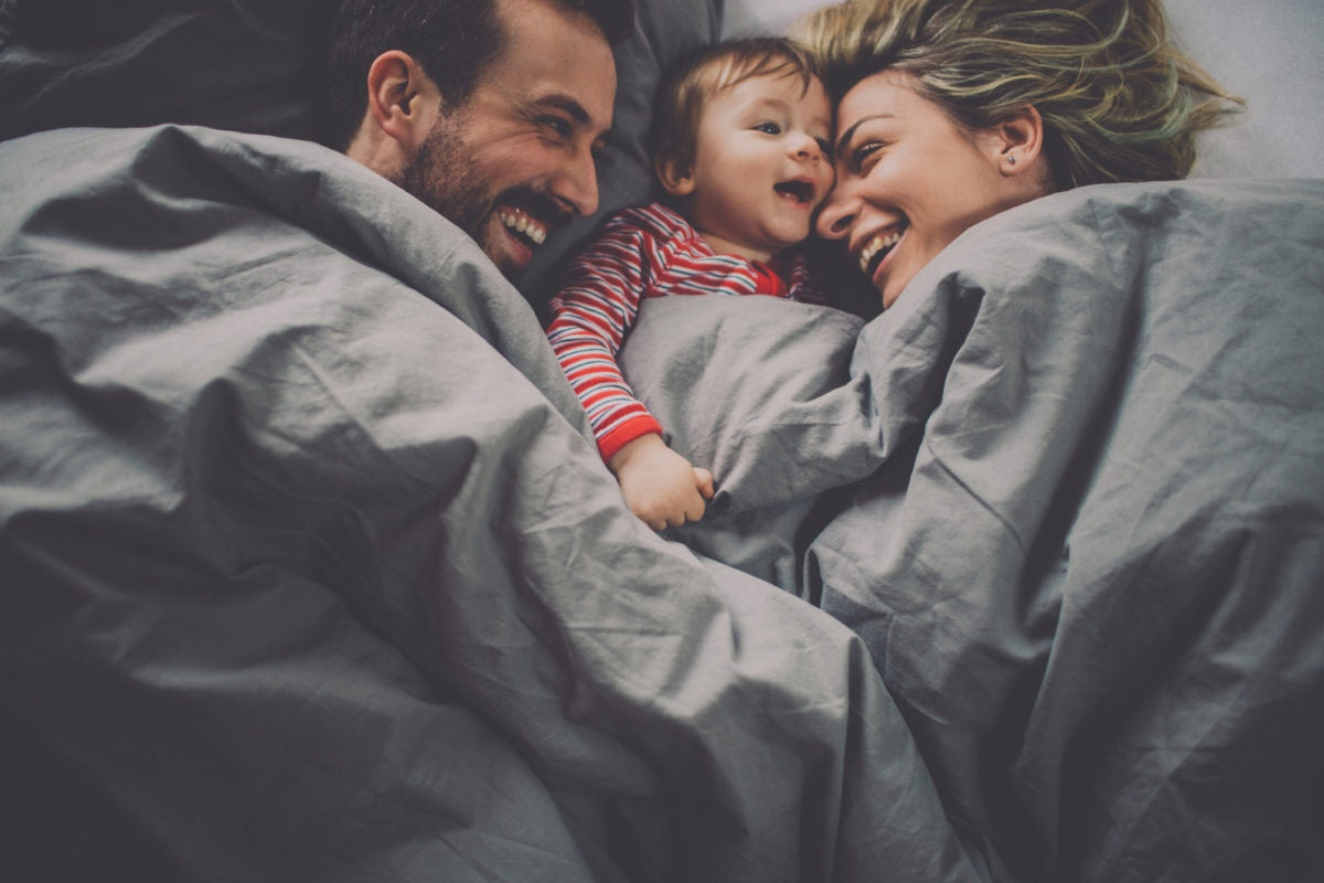 smiling parents with baby lying in between