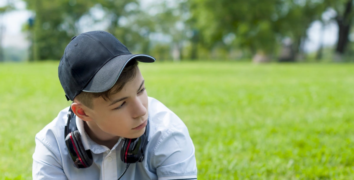 boy with headphones sitting on grass