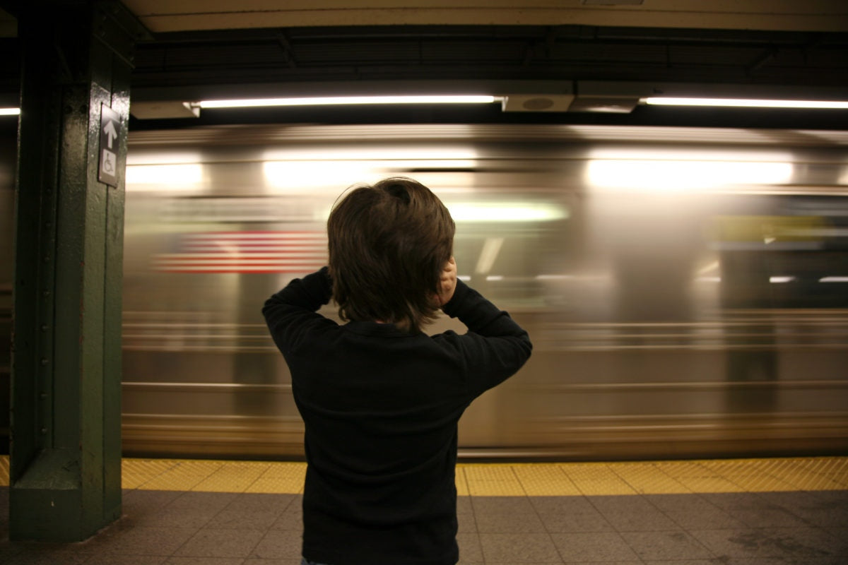 boy covering his ears at railway station