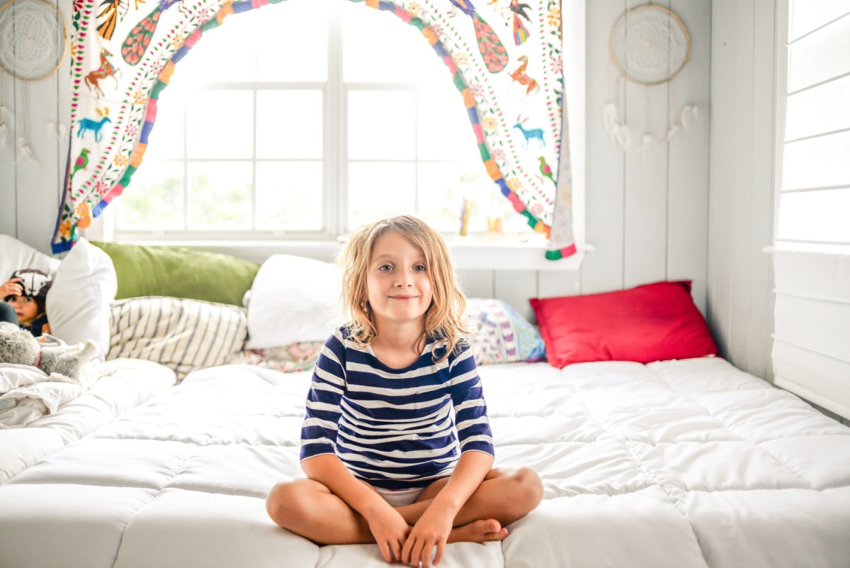 Happy little girl sitting on the bed 