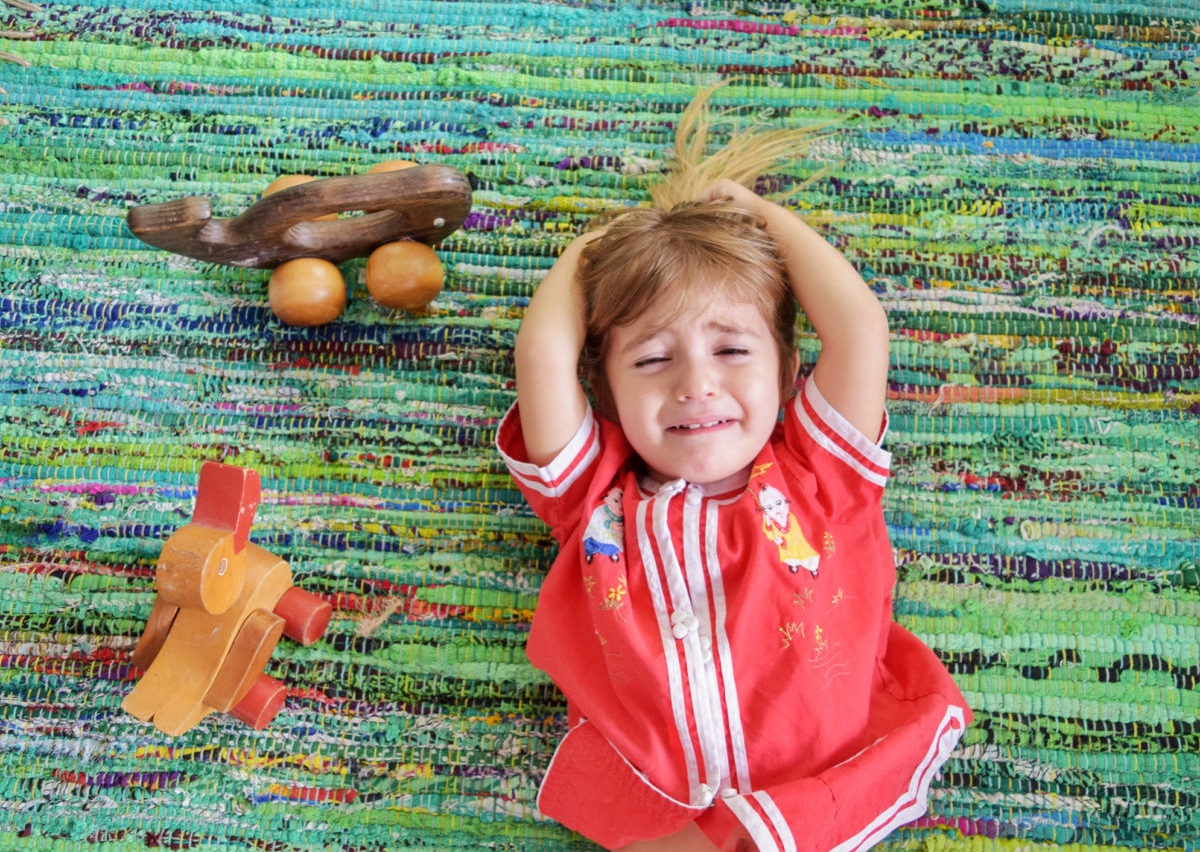 A child crying, beside two toys