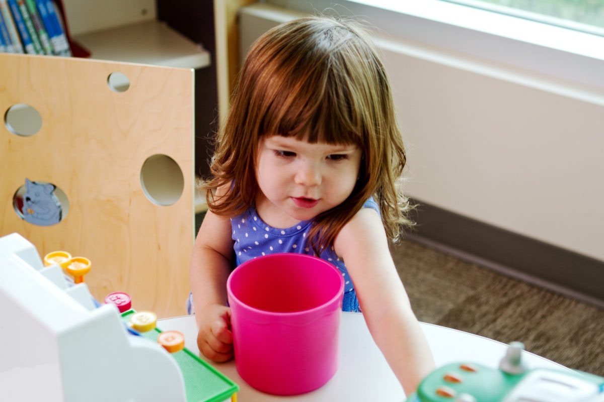 niña con el pelo rubio jugando con agua y colores en el jardín de infancia