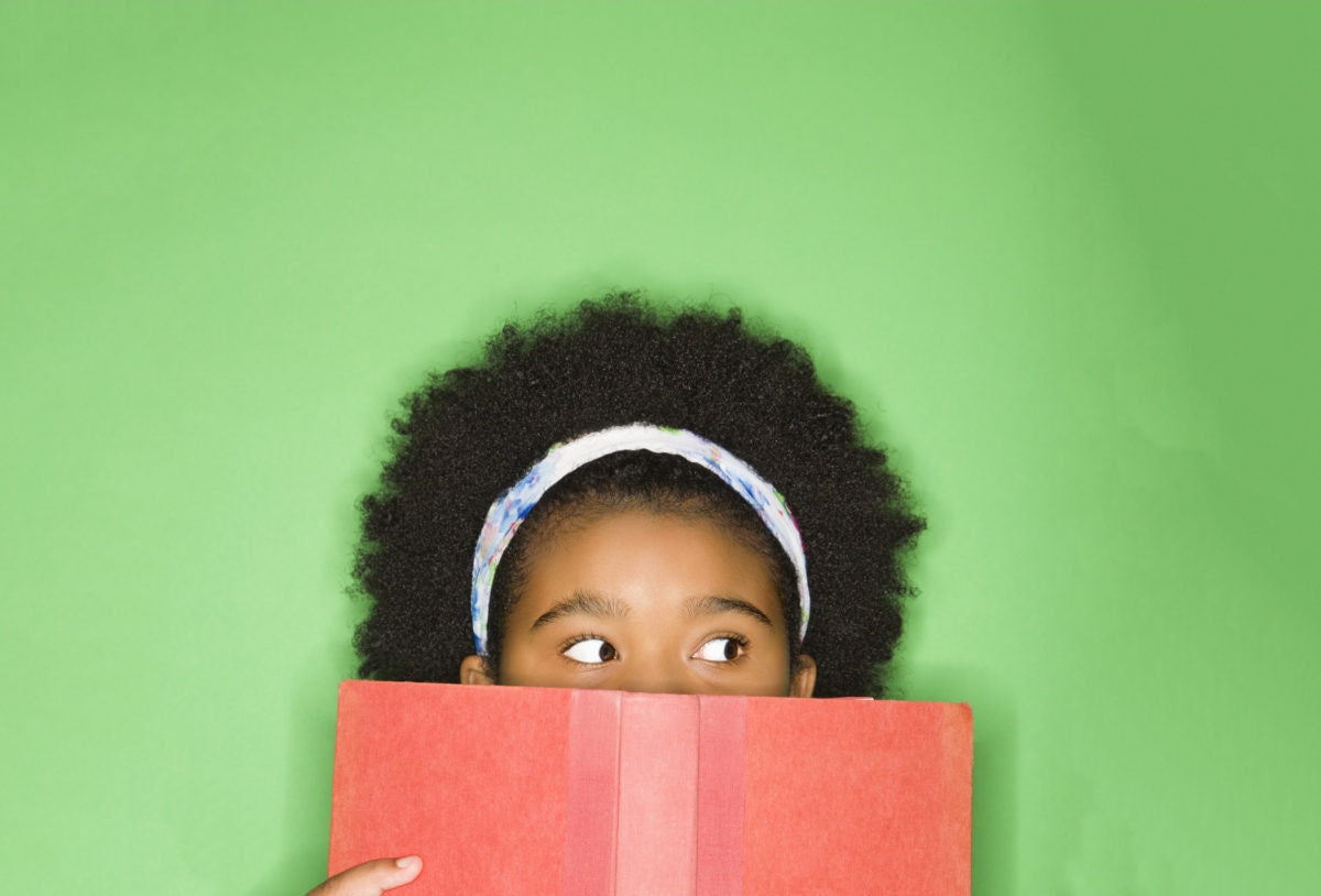 Young girl covering her mouth with book