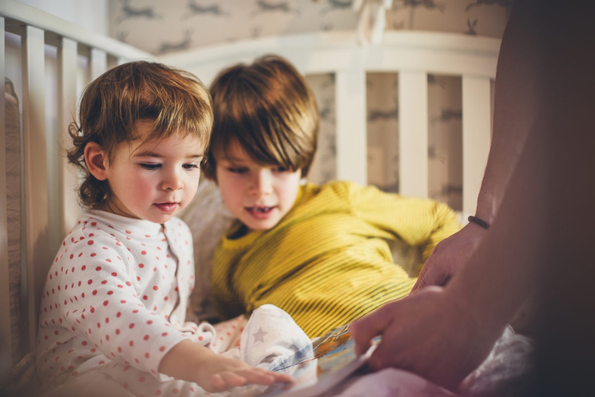 brothers inside the crib looking at the images in the book