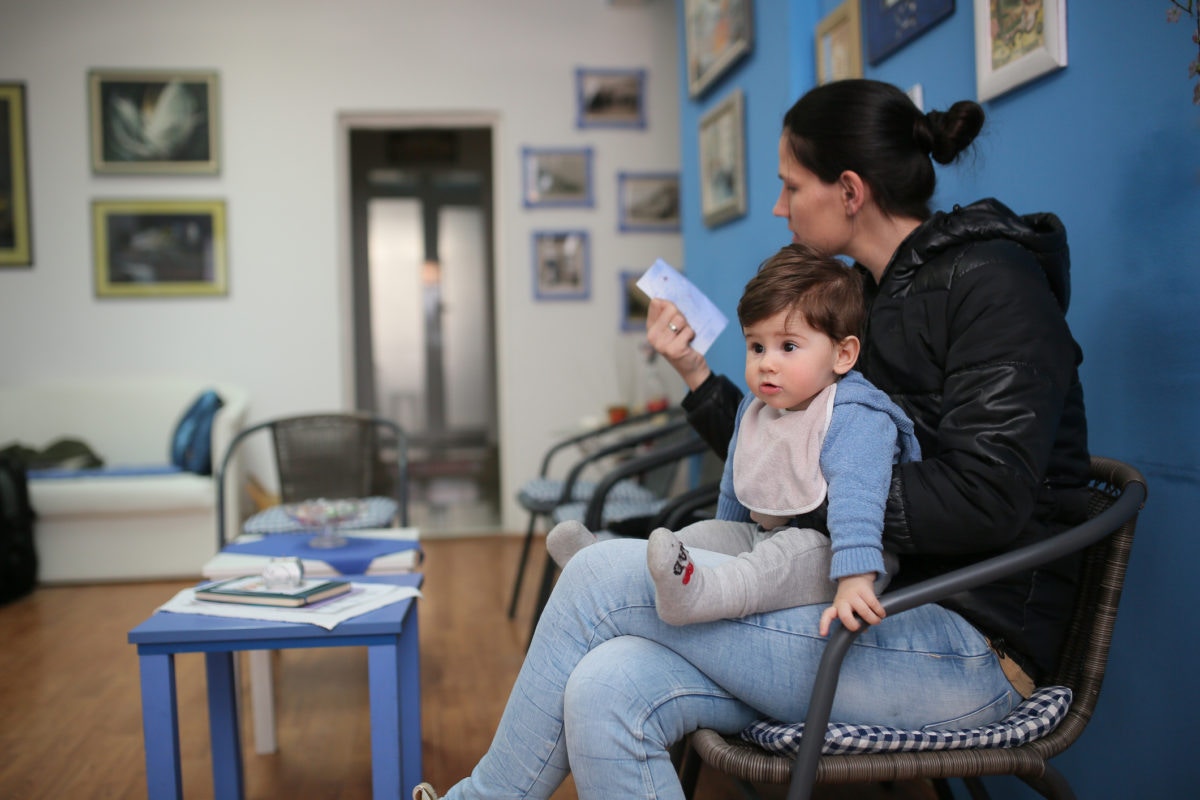 Mother is reading reciept with her baby on lap