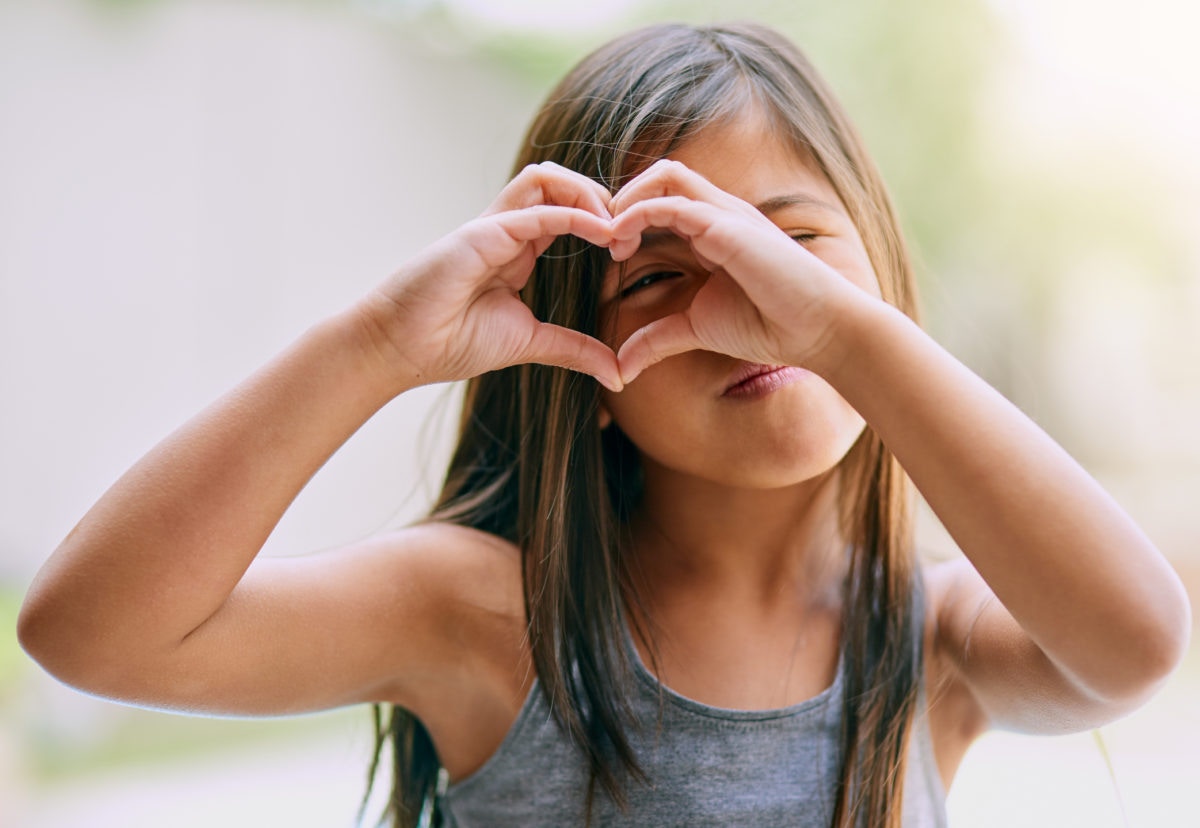 beautiful little girl showing heart symbol