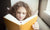 little girl with brown hair reading a book