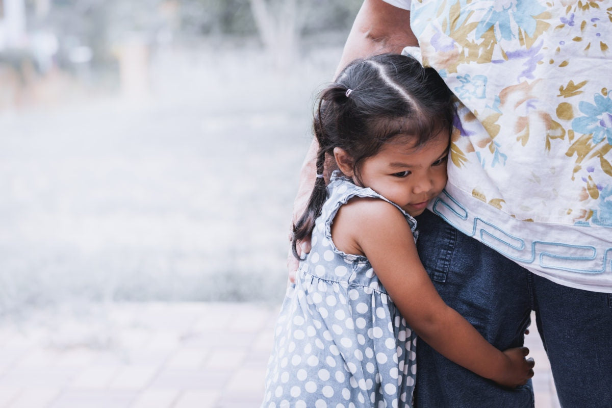 young girl holding adults leg