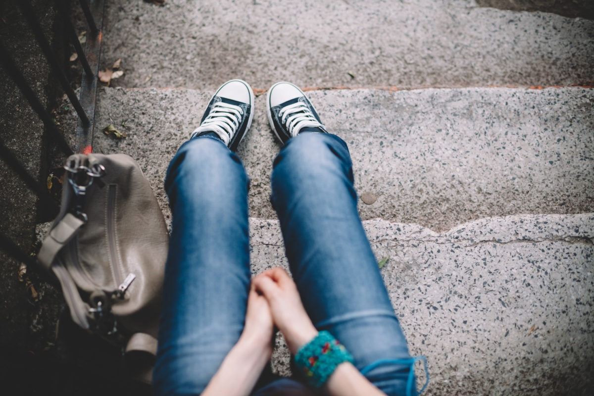 teenager sitting on steps with purse next to her