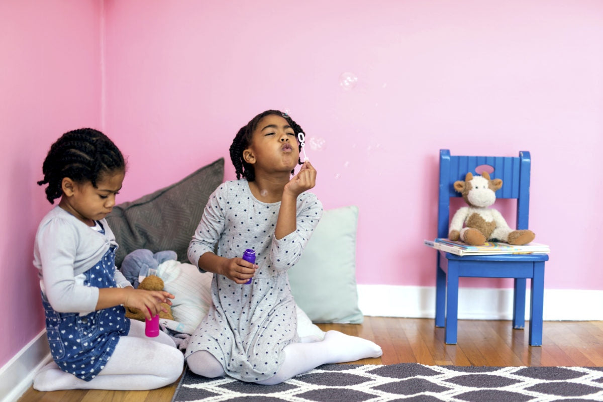 two girls blowing bubbles inside