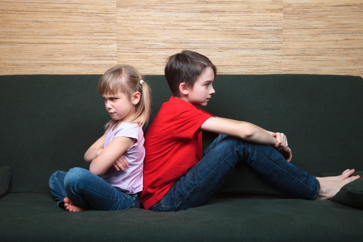 Two kids sitting back wards while one kid is seeing angrily