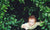 little boy standing in forest looking up