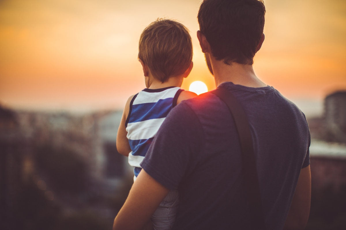 father holding his child with rising sun