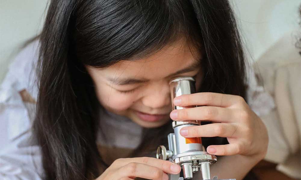 girl looking through a telescope