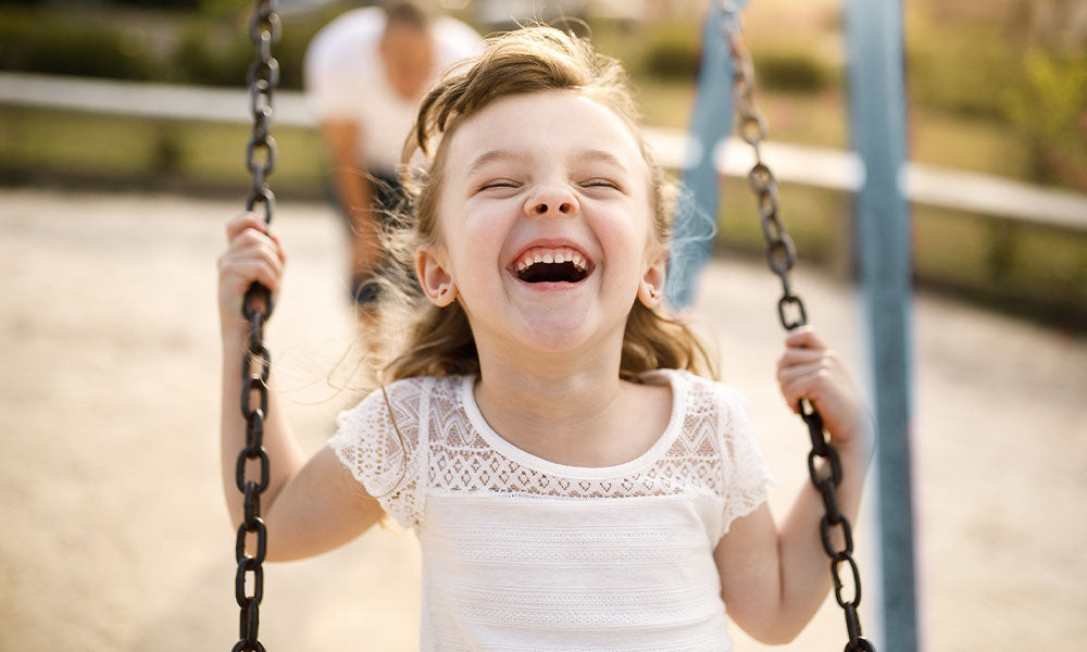 Smiling girl playing on the swing